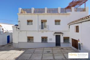 a white house with a black door in a courtyard at Homity Holidays - Gualchos - Casa Río Oculto in Gualchos +18 photos