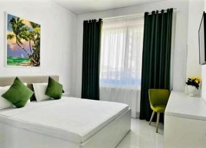 a bedroom with a large white bed with green curtains at Stefan Resort Mamaia Nord in Mamaia Sat/Năvodari +8 photos