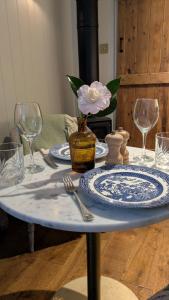 a table with plates and glasses and a flower in a vase at The Applehay in Constantine