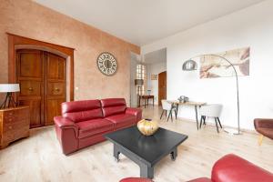 a living room with a red couch and a table at La Rose des Vents Le Vigan - Hyper centre - Parking in Albi