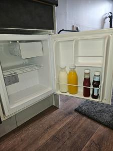 an open refrigerator with bottles of juice in it at The Golf Studio Woodhall Spa in Woodhall Spa