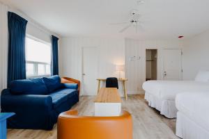 a living room with a blue couch and a bed at Riotel Perce in Perce
