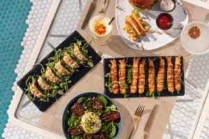 a table topped with plates of food and a salad at Dorado Ibiza - Adults Only in Playa d'en Bossa