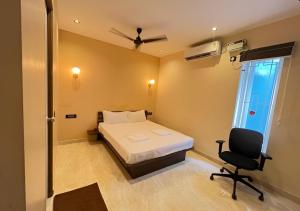 a bedroom with a bed and a chair and a window at The K Inn Wavefront in Mahabalipuram +7 photos