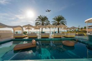 a resort swimming pool with a plane flying over it at Dorado Ibiza - Adults Only in Playa d'en Bossa +40 photos