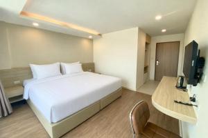 a bedroom with a large white bed and a television at Pinotel Prachuap - โรงแรมพิโนเทล ประจวบ in Prachuap Khiri Khan