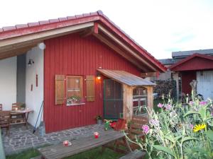 ein rotes Haus mit einer Bank davor in der Unterkunft Biehlerhof in Freudenberg