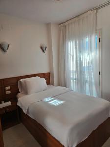 a bedroom with a large white bed with a window at نادي البحارة الدولي - International Seamans Club in Suez