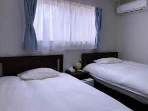a bedroom with two beds and a window with curtains at 竹の宿b湖まで徒歩4分の好立地最大7人宿泊可能 in Fujikawaguchiko