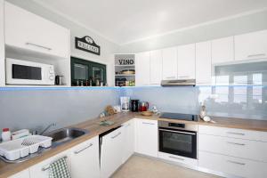 a white kitchen with a sink and a microwave at Apartments Vila Vino in Sveta Nedelja