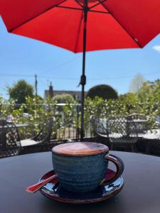 a cup of coffee sitting on a table with an umbrella at Colcombe Castle Hotel in Colyton