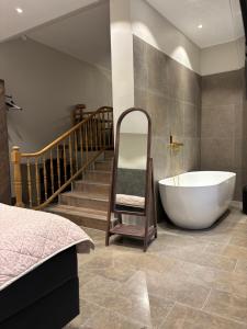 a bathroom with a tub and a chair and stairs at Hotell Visby Börs in Visby