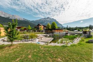a park with a pond and mountains in the background at Tirol Cabin by ALPAMI in Wildermieming