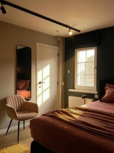 a bedroom with a bed and a chair and a mirror at B&B Maris Logies in Hasselt