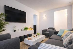 a living room with couches and a tv on a wall at D&E - PARIS-DISNEY - HOLIDAYS APARTMENT - APPARTEMENT DE VACANCES - 5 CHAMBRES- 5 SDB - 5 BEDROOMS - 5 BATHROOMS - Netflix in Champs-sur-Marne