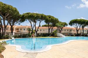 a swimming pool with trees and buildings in the background at Balconera 104 in Novo Sancti Petri