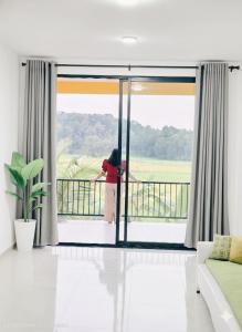 a woman standing on a balcony looking out the window at The Paddy Breeze Villa in Marukwatura