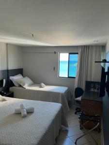 a hotel room with two beds and a window at Apartamento 1307 QUALITY HOTEL in Natal