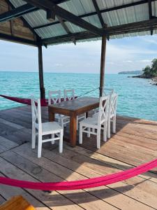 a wooden table and chairs on a deck with the ocean at Sea PoeTree in Koh Rong Sanloem