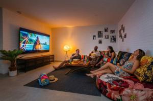a group of people sitting in a living room watching tv at Villa de lujo con jacuzzi, cine, billar y futbolín in Murcia