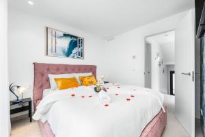 a white bedroom with a large white bed with orange pillows at Villa de lujo con jacuzzi, cine, billar y futbolín in Murcia