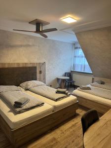 two beds in a room with a ceiling fan at Hotel MyLord in Soltau