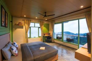 a bedroom with a bed and large windows at PACK Dharamkot in McLeod Ganj