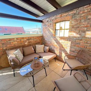 a patio with a couch and chairs and a brick wall at Tiny Haus in Bad Sulza