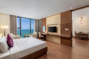 a hotel room with a bed and a dining room at Rosamia Da Nang Hotel - My Khe Beachfront Luxury in Danang