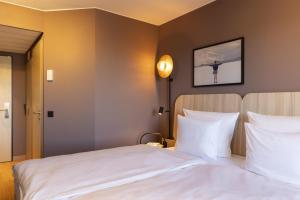 a bedroom with a bed with white sheets at Scandic Stuttgart Europaviertel in Stuttgart