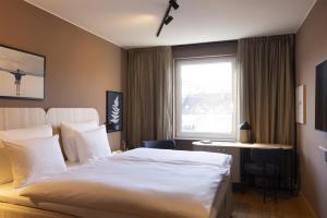 a hotel room with a bed and a desk and a window at Scandic Stuttgart Europaviertel in Stuttgart +48 photos