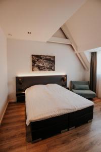 a bedroom with a bed and a chair at Hotel Tholen in Tholen +16 photos