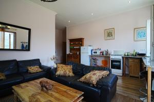 a living room with a black leather couch and a table at casa do campinho in Fundoais