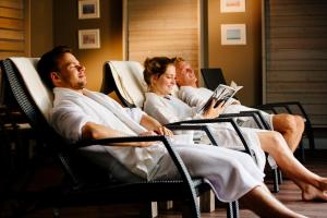 three people sitting in chairs reading a book at Beach Motel St. Peter-Ording in Böhl