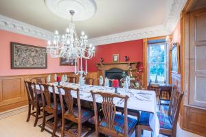 a dining room with a table and chairs and a chandelier at The Doune, Luxury Traditional Country House with hot tub in Inverness