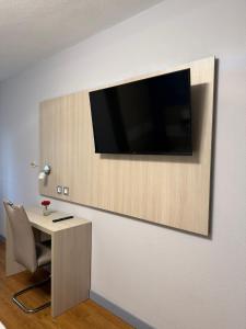 a room with a desk and a television on a wall at Hotel Bahia in Gijón