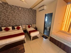 a room with two beds and a couch and a window at Hotel Hanuman Palace-450 meter Khatu Shayam Ji Temple in Khātu