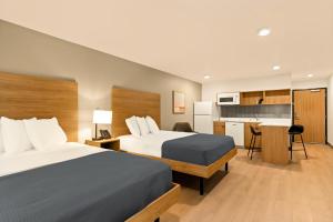 a hotel room with two beds and a kitchen at LivAway Suites Phoenix-Glendale in Glendale