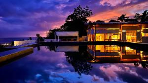 a house with a swimming pool at sunset at Siquijor Jade ocean resort in Siquijor