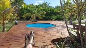 a person with their feet up on a wooden deck with a pool at Cabane Autentikaz in Saint-François