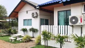 a white house with a white fence and a fan at Hideout Homestay in Ban Rai Pa Yoe