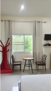 a bedroom with a bed and a table and a window at Hideout Homestay in Ban Rai Pa Yoe