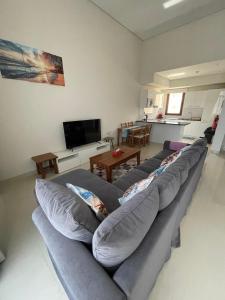 a living room with a gray couch and a television at Hakuna Matata Villa - BF 515A in Muscat +8 photos