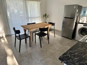 a wooden table and chairs in a kitchen with a refrigerator at Departamento y aire libre in General Pico +2 photos