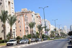 a street with cars parked on the side of a building at R suite in Netanya