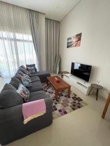 a living room with a couch and a tv at Hakuna Matata Villa - BF 515A in Muscat