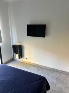a bedroom with a bed and a tv on the wall at Departamento y aire libre in General Pico