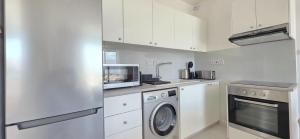 a kitchen with white cabinets and a washer and dryer at White Aura by Staycom in Paphos +2 photos