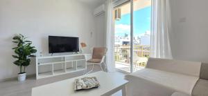 a white living room with a tv and a couch at White Aura by Staycom in Paphos