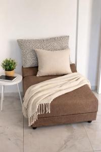 a brown couch with a blanket and a table at Romy secrets in Netanya